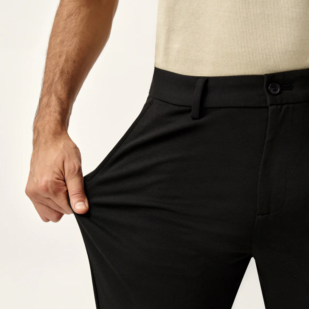 Person wearing black pants with a beige background