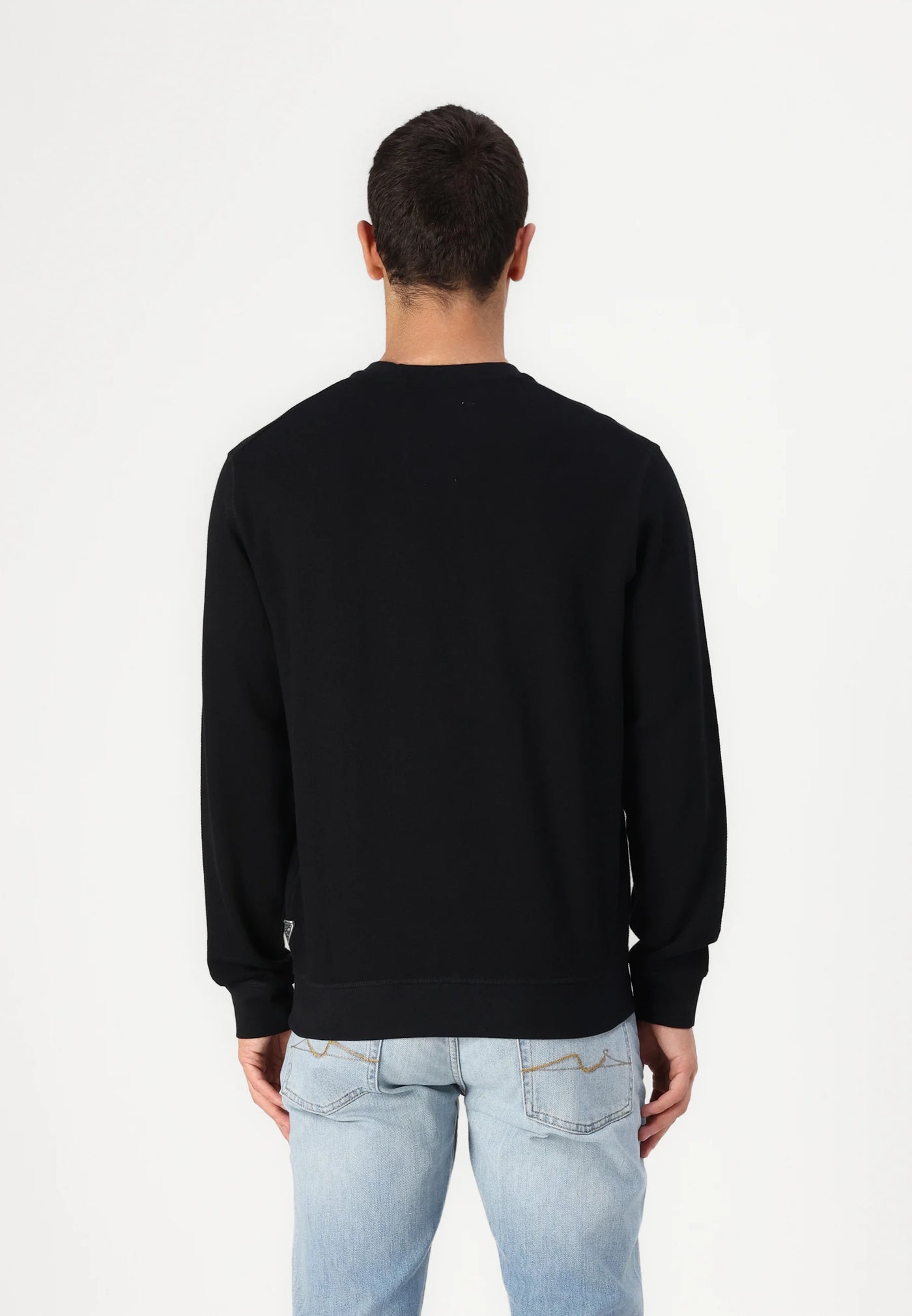 Back view of a person wearing a black sweatshirt and light blue jeans.