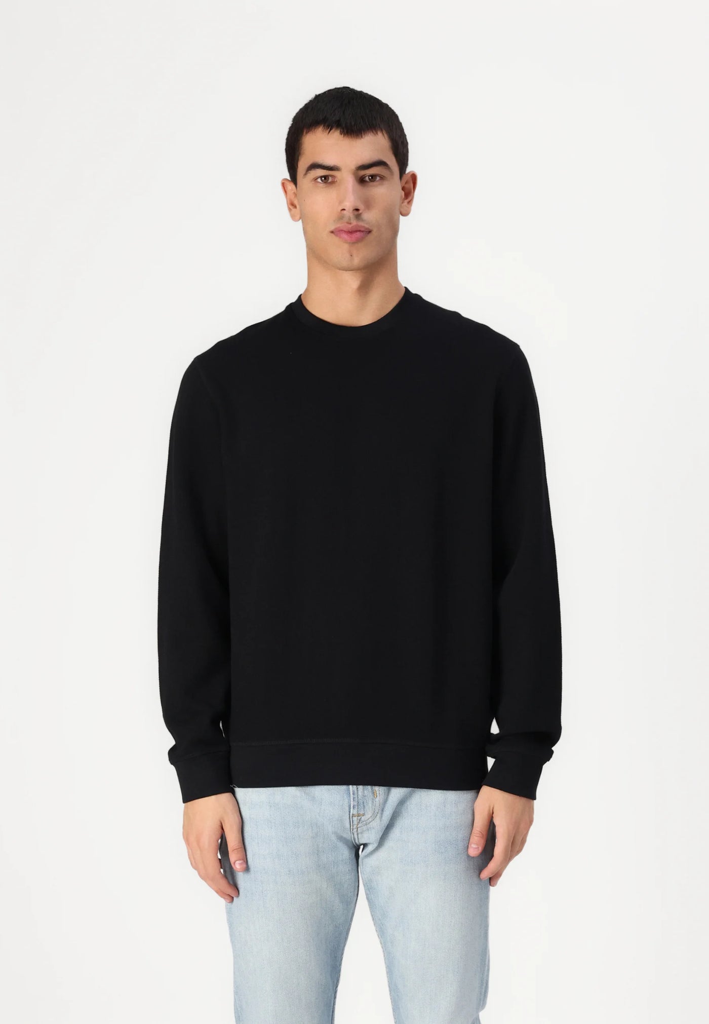 Man wearing a black sweatshirt and light blue jeans.