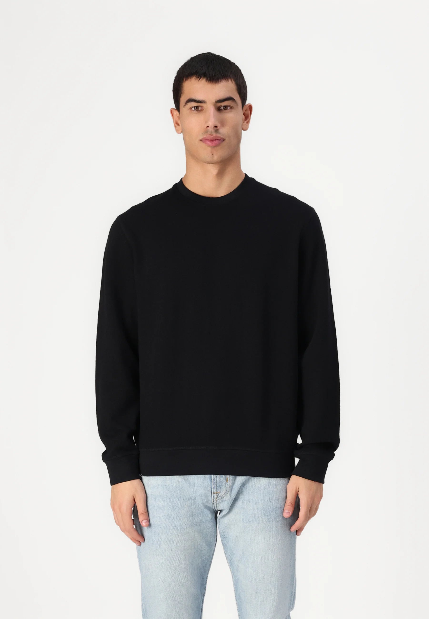 Man wearing a black sweatshirt and light blue jeans.