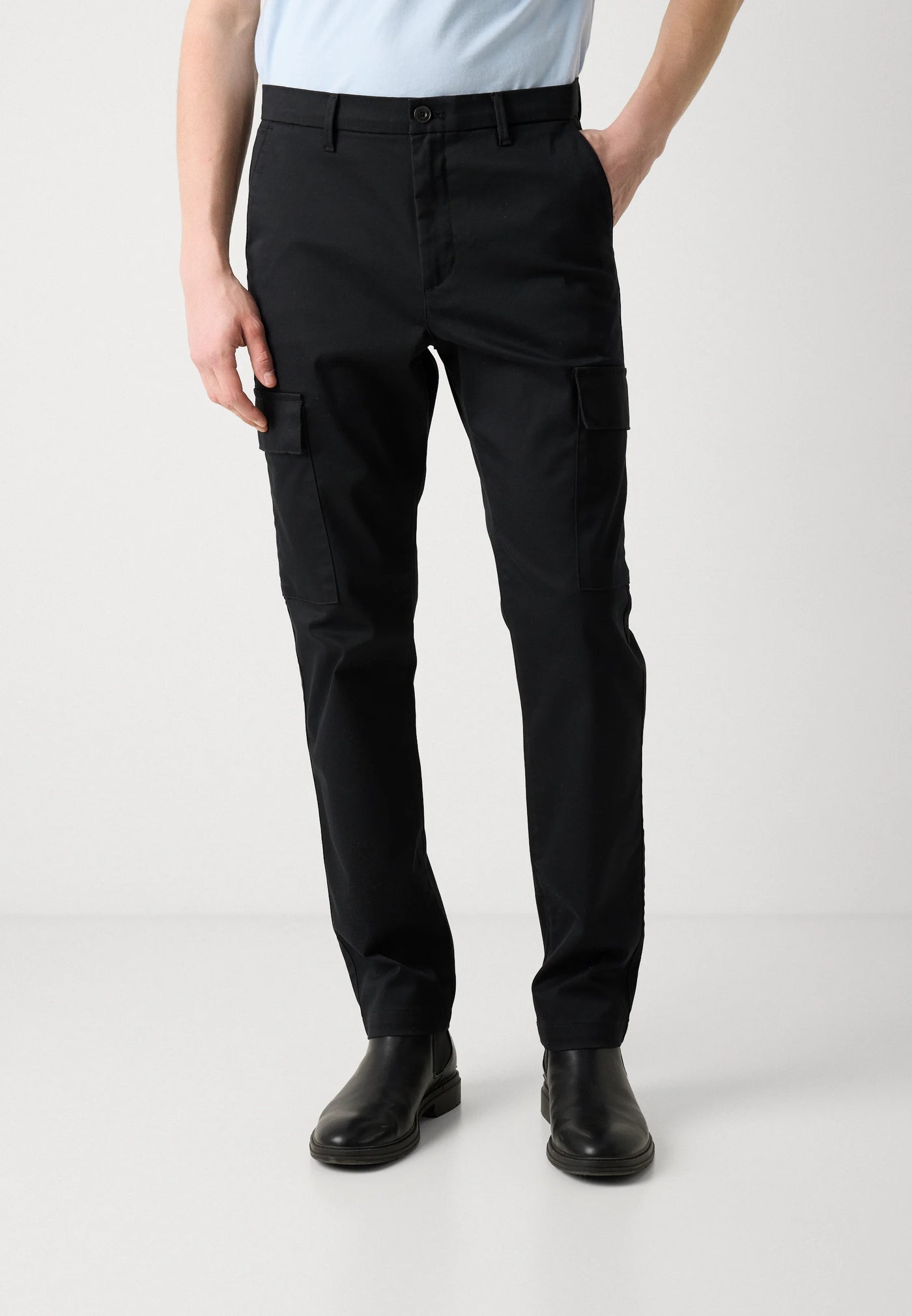 Person wearing black cargo pants on a white background